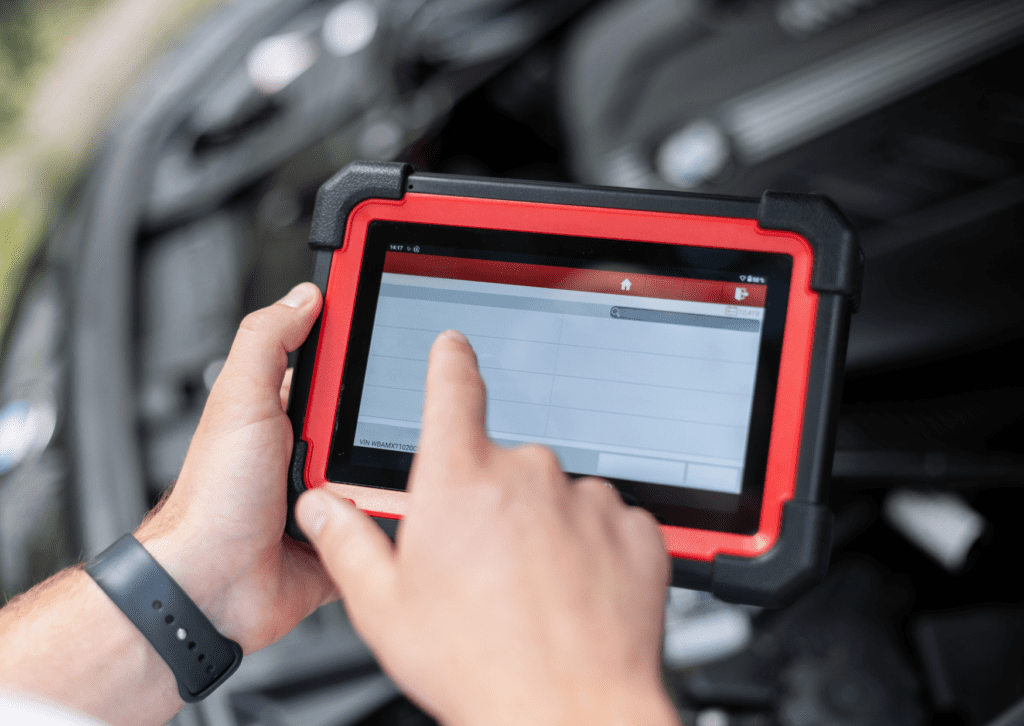 Mechanic uses a diagnostic tablet inside a car to scan vehicle systems during service work 