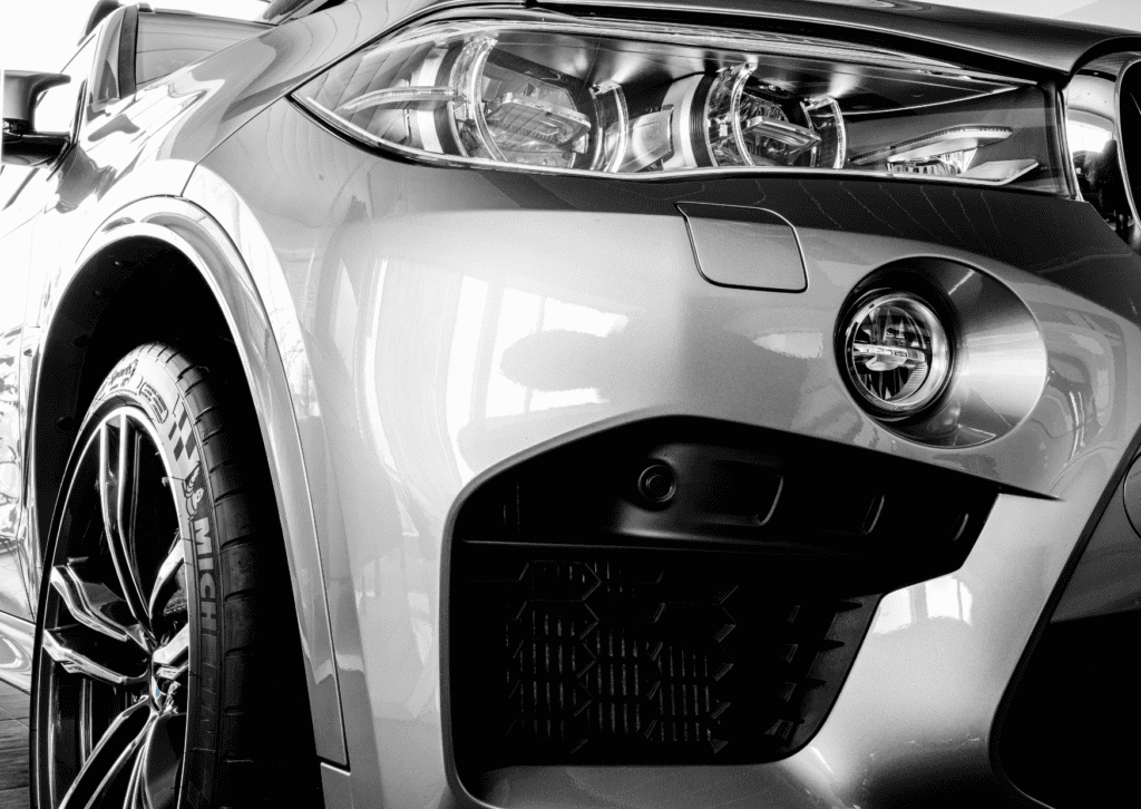 Close-up of a BMW front headlight, wheel, grille, and bumper showing detailed exterior styling 
