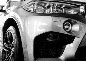 Close-up of a BMW front headlight, wheel, grille, and bumper showing detailed exterior styling