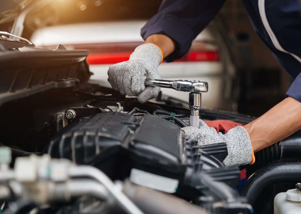 Auto mechanic performing Volkswagen repair under the hood using a ratchet and socket wrench 