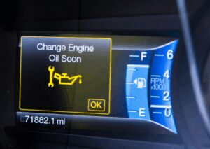 Dashboard screen showing oil change indicator warning message, odometer reading 71,882 miles, and fuel and RPM gauges.
