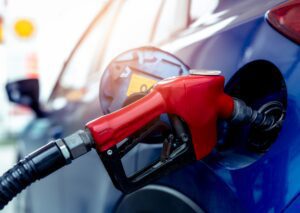 Red gas pump nozzle fueling a blue car at station, illustrating fuel system issues and common maintenance concerns.